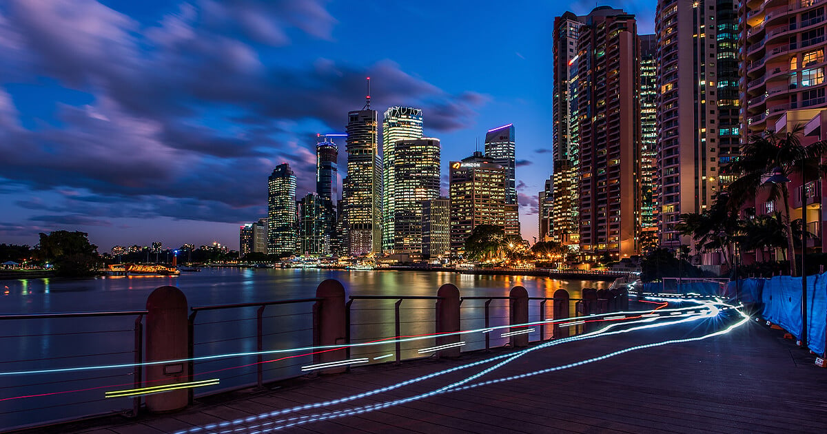 Gratte-ciel de la ville de Brisbane se reflétant sur la rivière et les pistes cyclables sur le trottoir au crépuscule