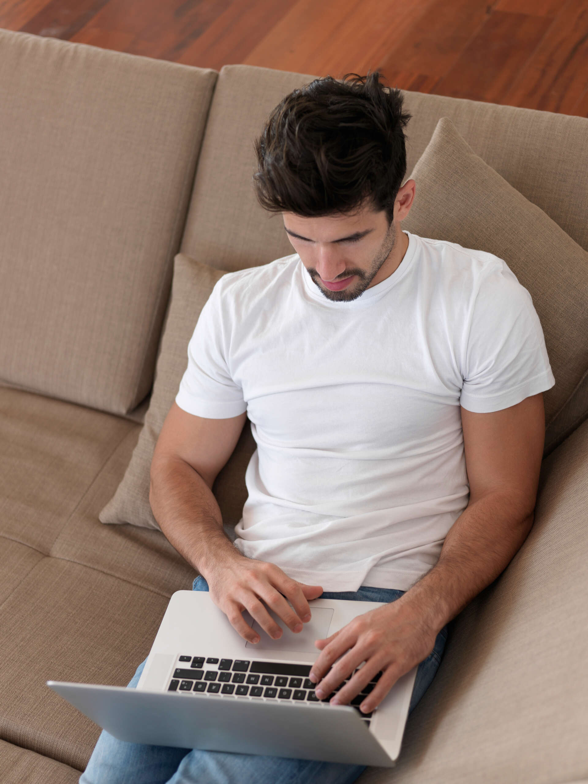 Homme sur un canapé avec un ordinateur portable calculant les frais de déménagement 